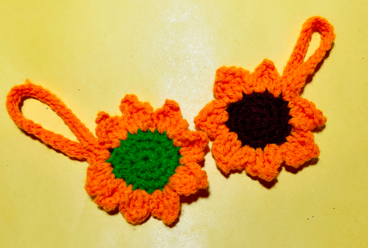 His & Hers Handmade Crochet Sunflower Keychains – A pair of vibrant orange and green knitted flower keychains, perfect for couples or as a thoughtful gift, set against a bright yellow background.
