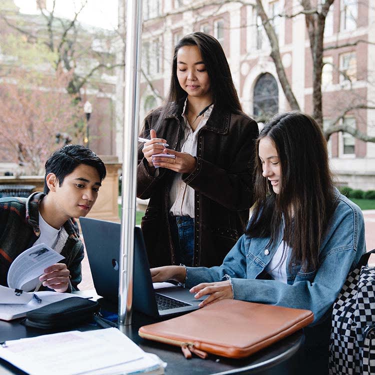 young people studying together at a table outdoors