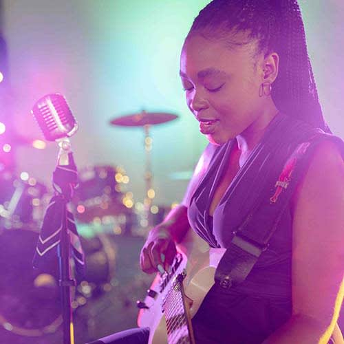woman sitting and playing guitar on stage during a concert