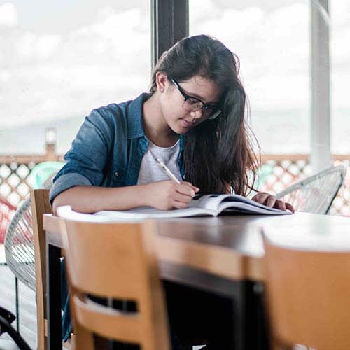 girl with long hair studying a book at a cafe