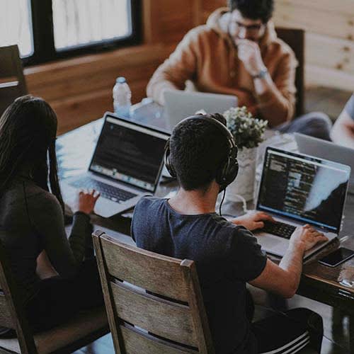 four people working at a table on laptops