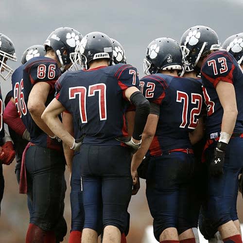group of football players huddling in uniform