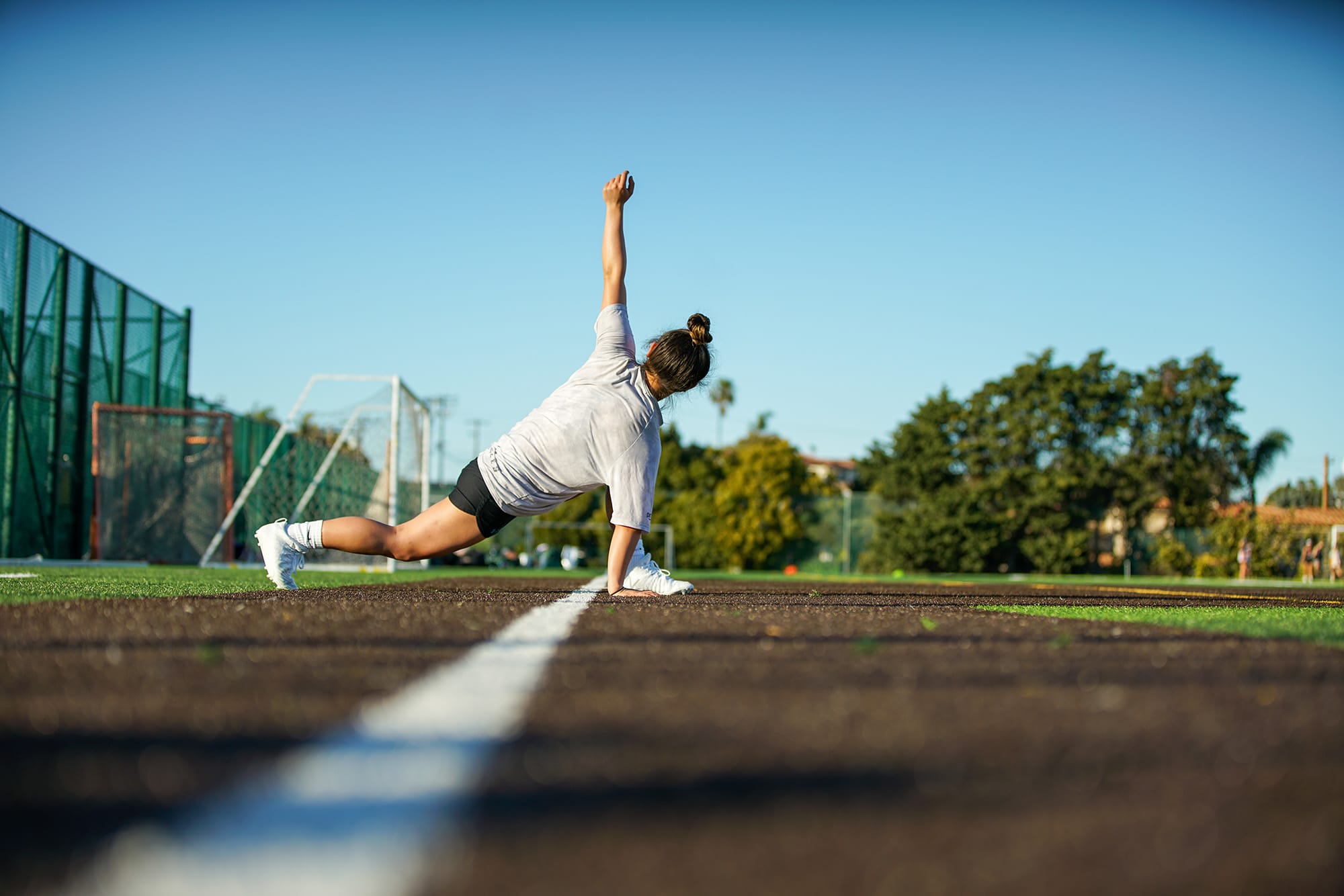 young woman doing exercise outside on a field