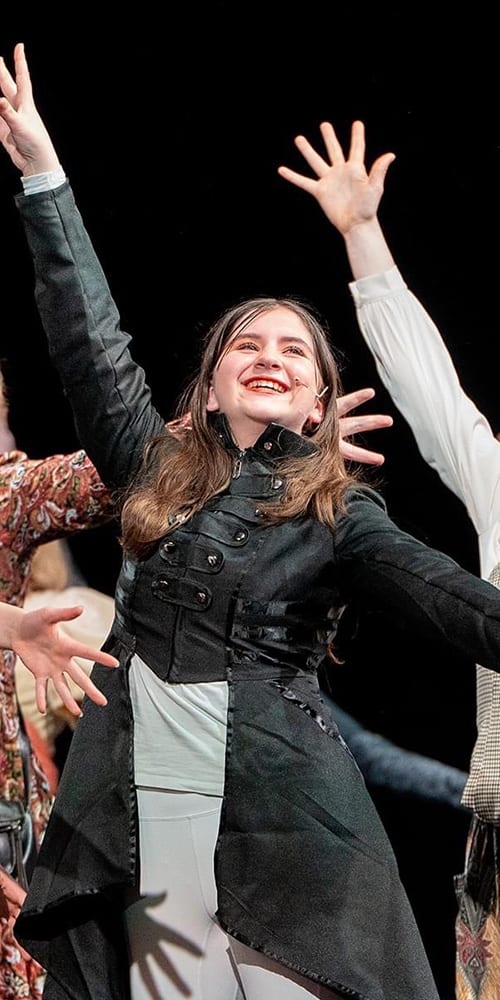 theater kids finishing performance on stage with a large smile on their faces