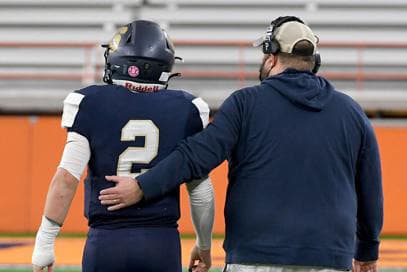 Football coach walking with player and showing leadership.