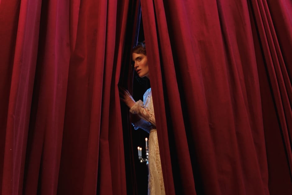 an image showing an actress peeping behind a theatre curtain