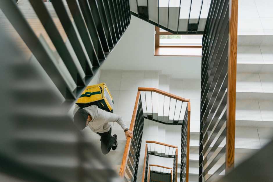an image showing a guy climbing stairs in a building with a big backpack on his bag