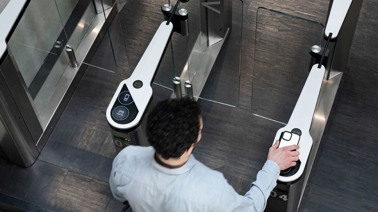 An image of a man unlocking a turnstile with his phone using Kisi