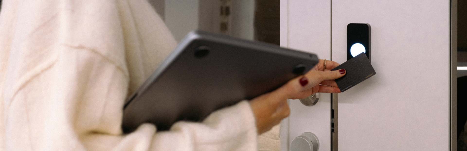 Person unlocking a door with an access badge while holding a laptop