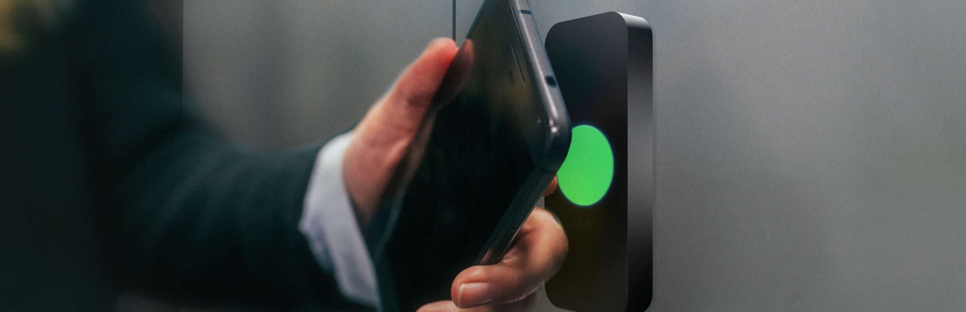 Person unlocking an elevator by tapping their phone to the Kisi access control reader