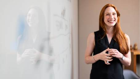 An image showing a woman smiling while giving a presentation