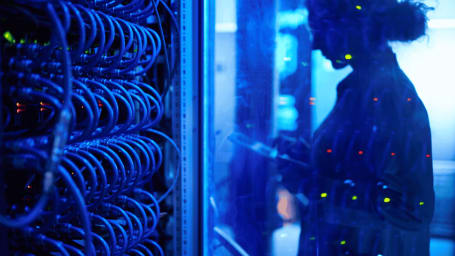 An image showing a woman in a server room working on her tablet