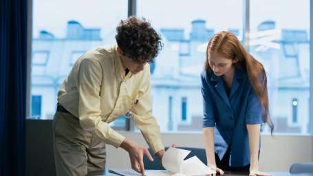 An image of a man showing a draft to a woman in a publishing house