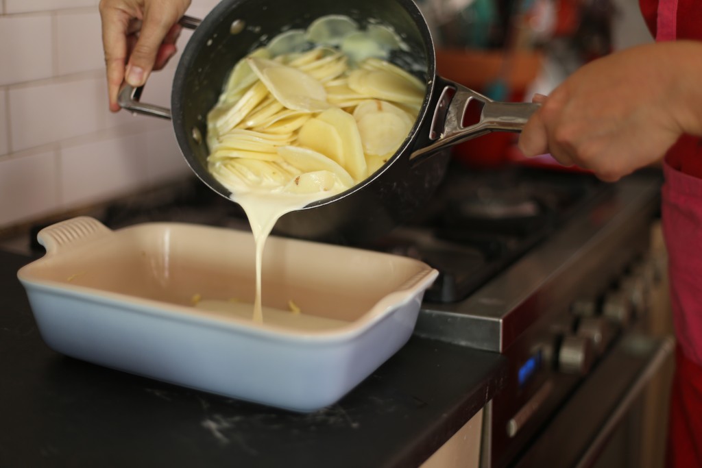 Dauphinoise pouring potatoes in