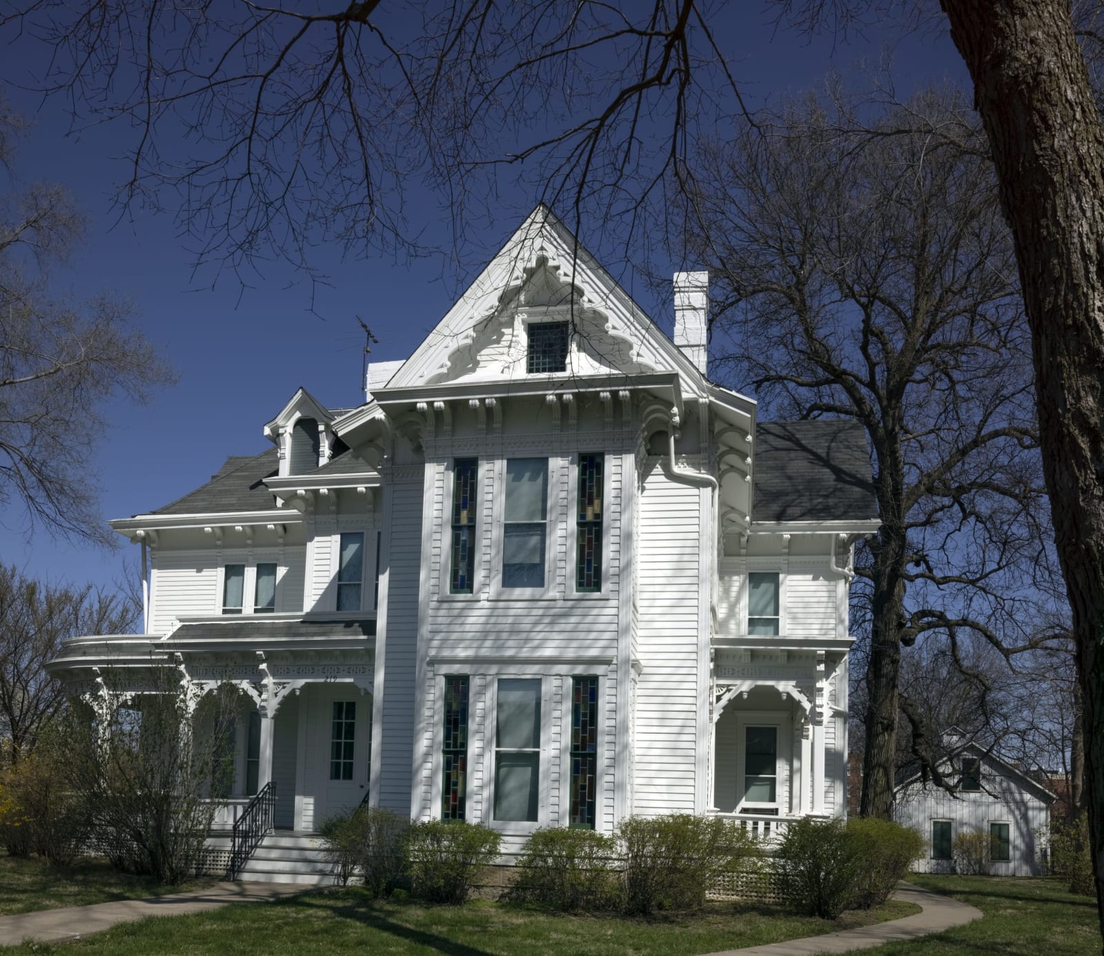 The white Victorian Truman Home on North Delaware Street in Independence, framed by bare trees.