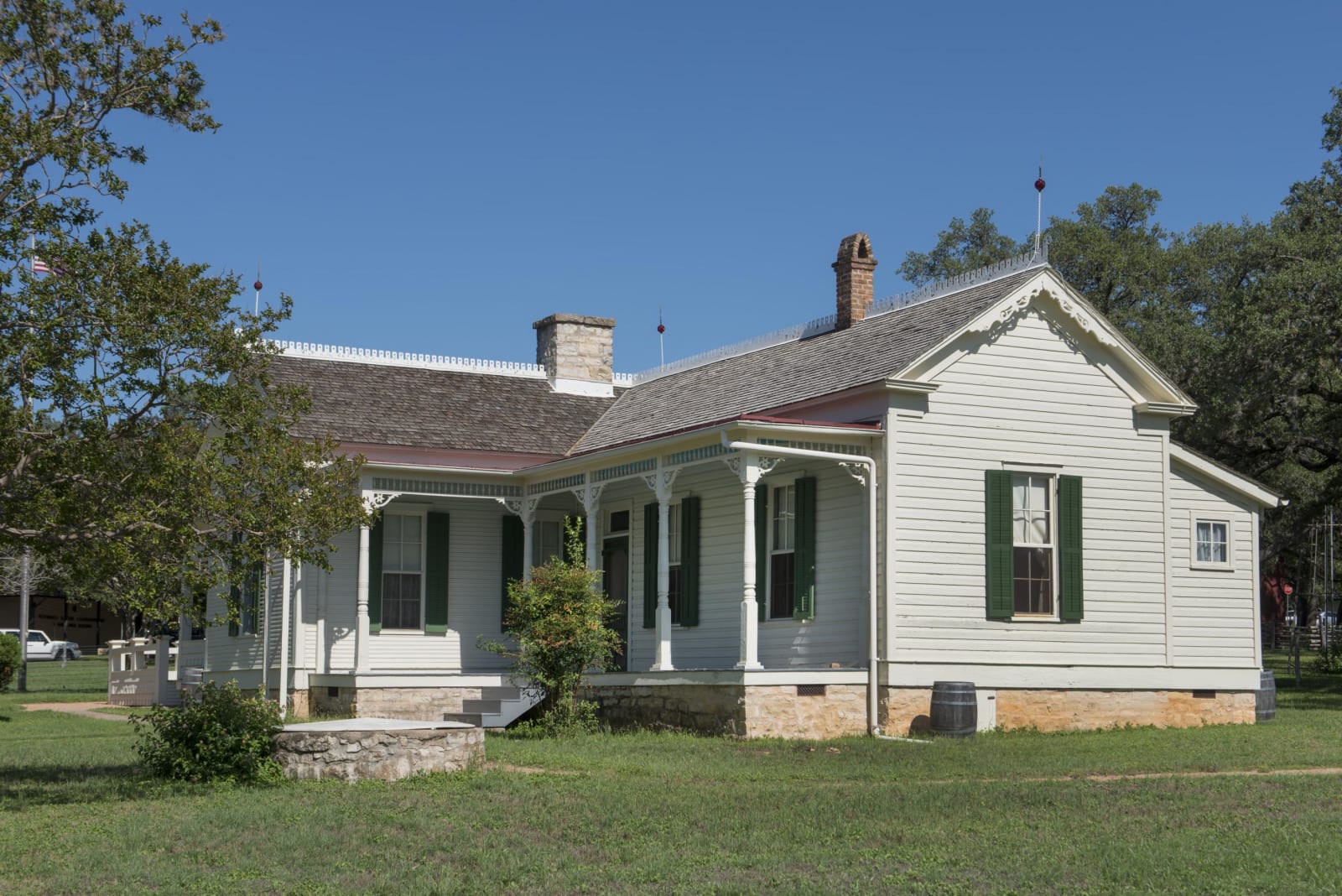 The white frame boyhood home of Lyndon B. Johnson in Johnson City, with green shutters and a front porch, on a green lawn.