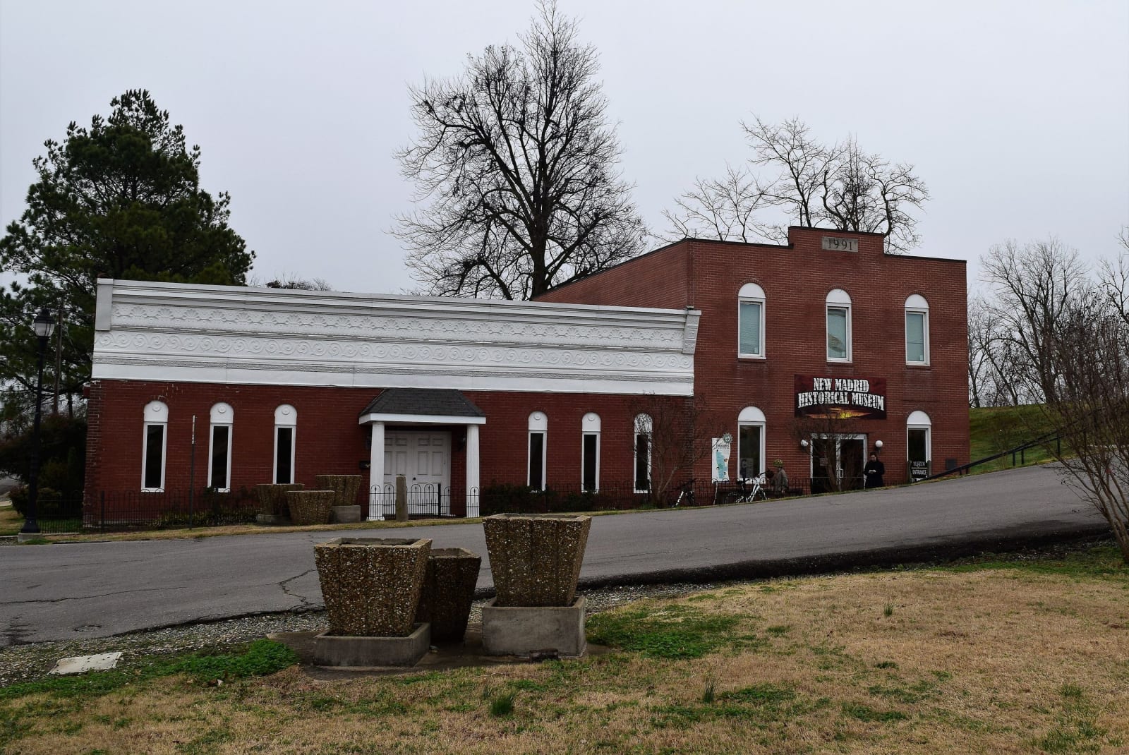 The red brick New Madrid Historical Museum with its arched windows beside a white annex.
