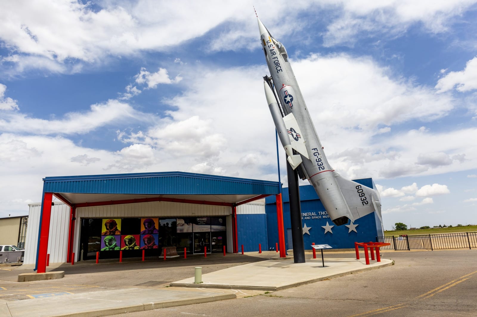 An F-104 jet mounted on a tall pylon beside the red, white and blue entrance of the Stafford Air and Space Museum in Weatherford.