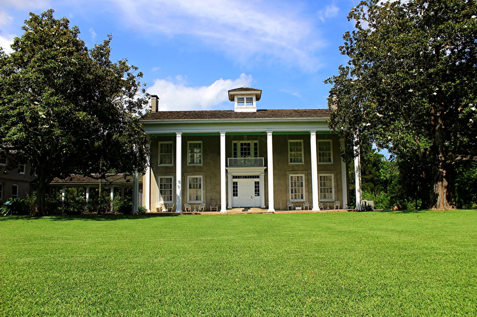 The white-columned plantation house at Varner-Hogg near West Columbia, behind a wide lawn framed by large trees.