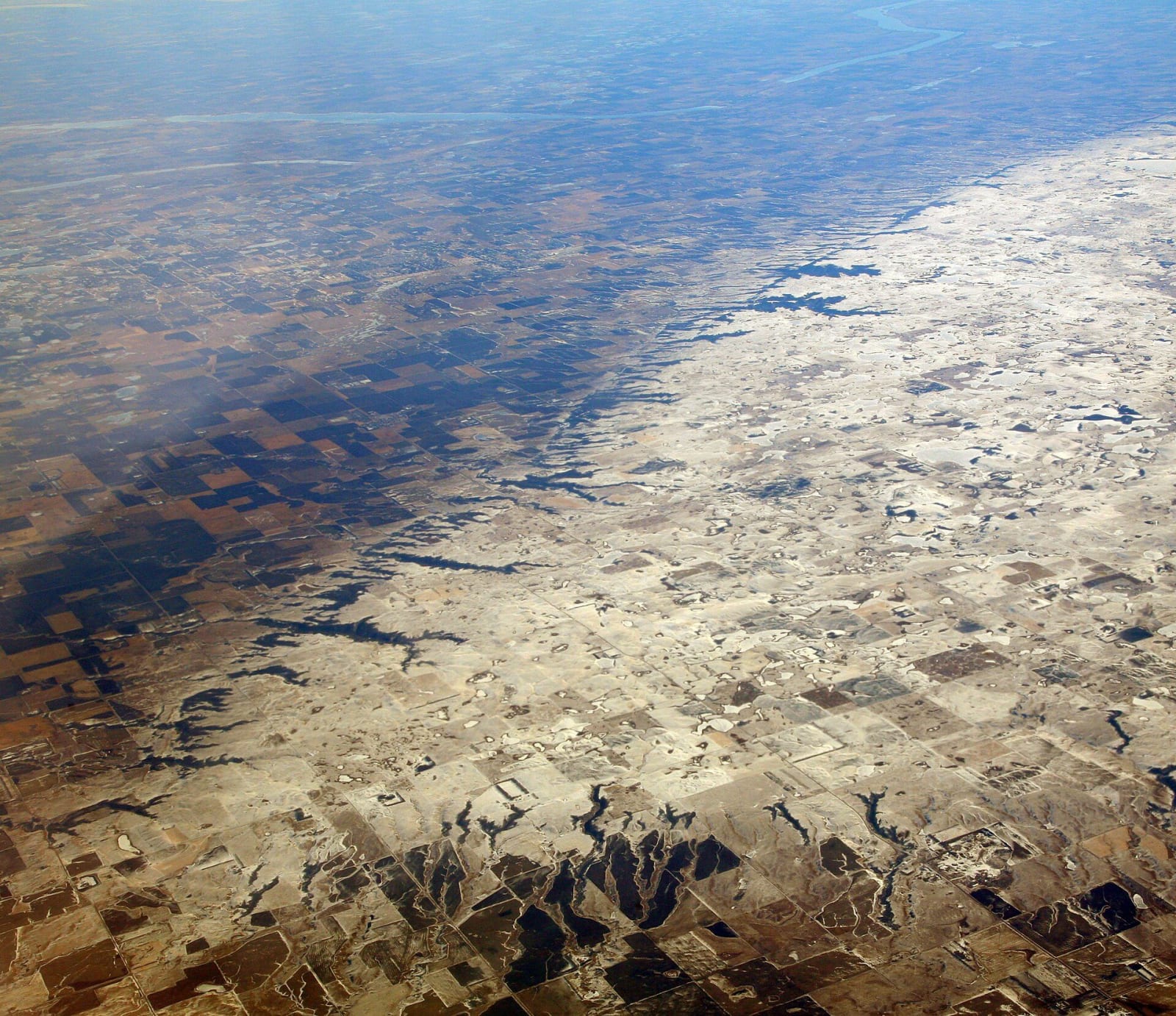 An aerial view of the flatiron-shaped Coteau des Prairies plateau, dusted with snow, rising above the patchwork farmland around it