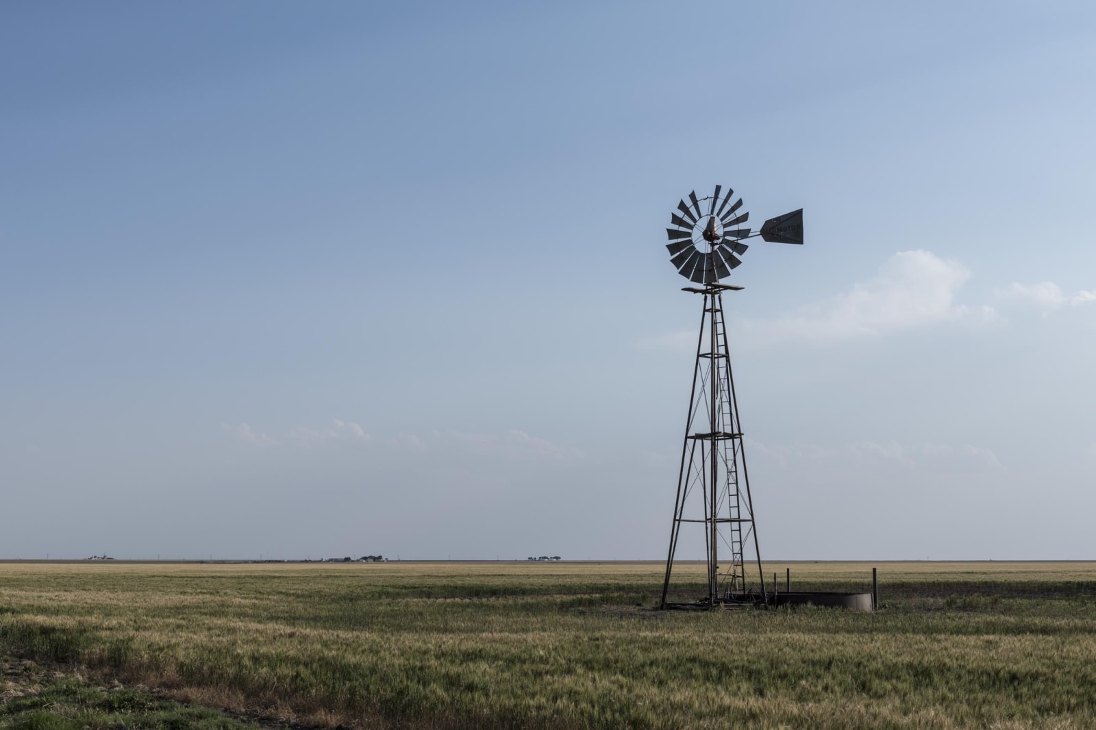 A lone windmill standing over flat grassland under a wide sky in rural Gray County, the county of the McLean camp.