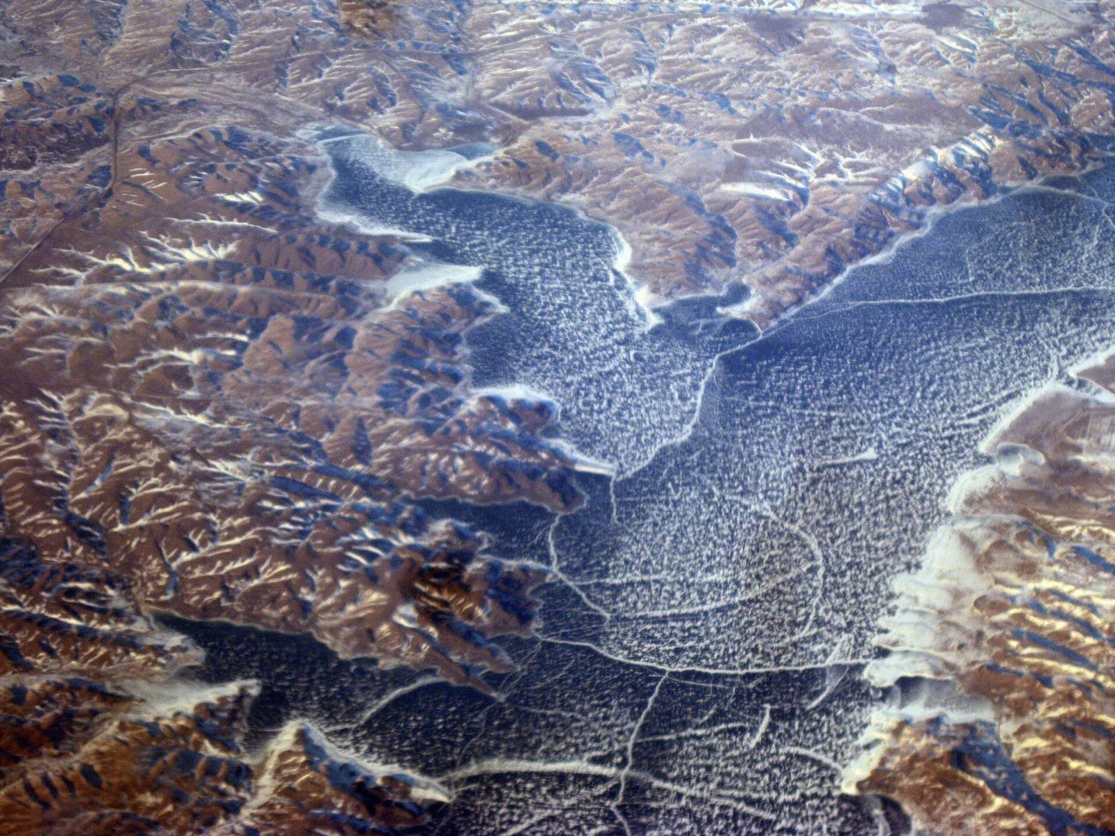 Lake Oahe frozen in winter, seen from the air, its icy arms reaching up the flooded side valleys between bare hills