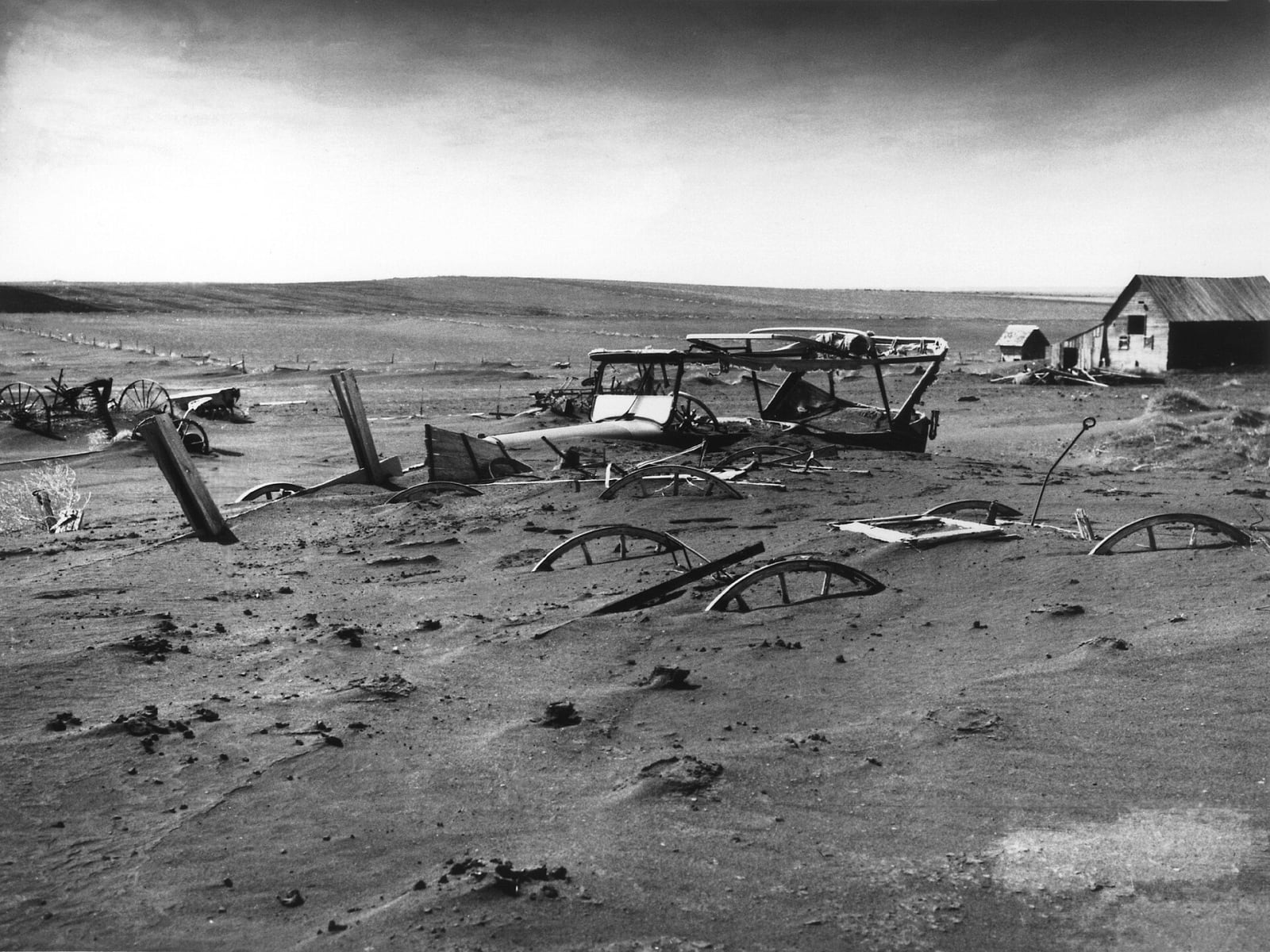 Farm machinery half buried by drifted soil in a barn lot at Dallas, Gregory County, during the Dust Bowl in 1936