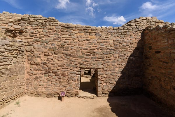 A small doorway through a masonry wall in a roofless room of the West Ruin at Aztec Ruins