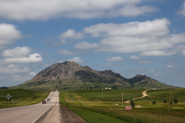Bear Butte rising alone above the prairie at the end of a straight two-lane road