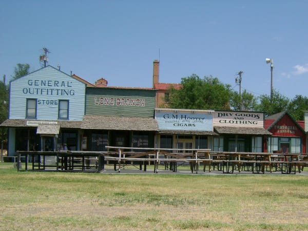 The false-front shops of the Front Street replica at Boot Hill Museum, with picnic tables on the lawn before them.