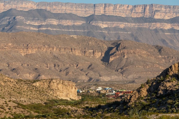 The village of Boquillas del Carmen in a desert valley below layered cliffs of the Sierra del Carmen, seen from the Texas side.