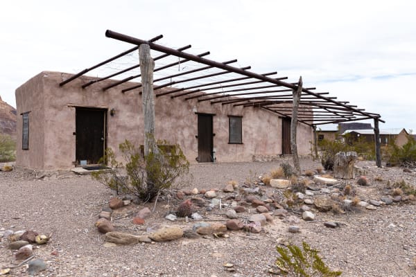 A small adobe house with a wooden ramada and stone-edged yard at the Castolon Historic District in Big Bend National Park.