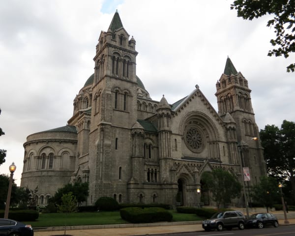 The gray stone Cathedral Basilica of Saint Louis on Lindell Boulevard, with its towers and dome, seen from a corner.