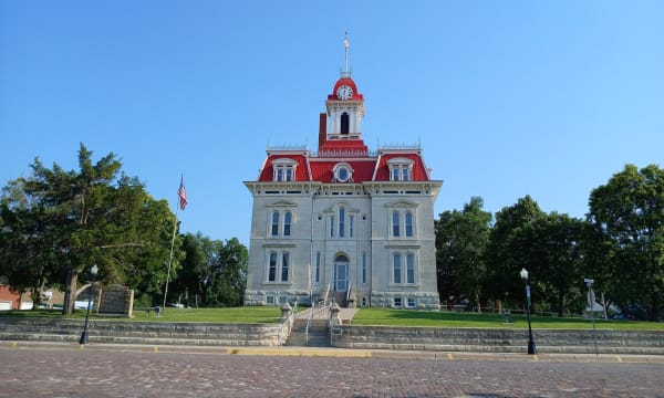 The limestone Chase County Courthouse in Cottonwood Falls, with its red mansard roof and clock tower, at the end of a brick street.