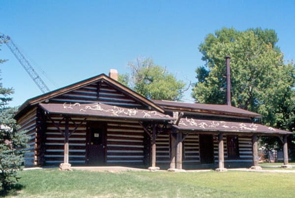 Charlie Russell's log cabin studio at the C. M. Russell Museum in Great Falls, a deep porch on peeled-log posts under a gabled roof