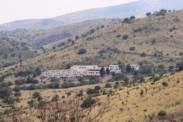 The white adobe Indian Lodge tucked into a grassy, oak-dotted canyon in Davis Mountains State Park.