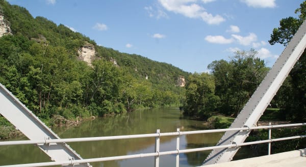 The Big Piney River and its wooded bluffs seen between the steel trusses of the Devils Elbow Bridge.