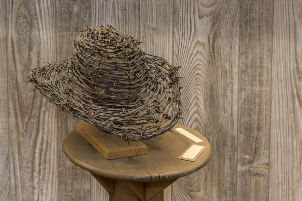 A cowboy hat woven from strands of barbed wire, displayed on a wooden stand at the museum in McLean.