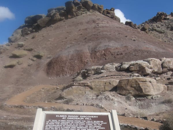 The capped slope of Dinosaur Hill near Fruita, with the trail sign about Elmer Riggs's dig in the foreground