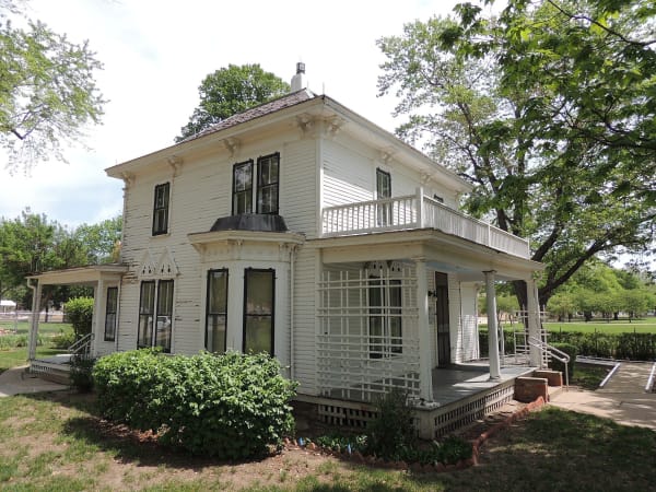 The white two-story Eisenhower boyhood home in Abilene, with its porches and shade trees.