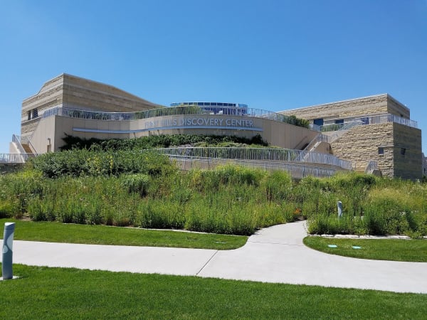 The terraced limestone Flint Hills Discovery Center in Manhattan, above a planted prairie garden and a curving walk.