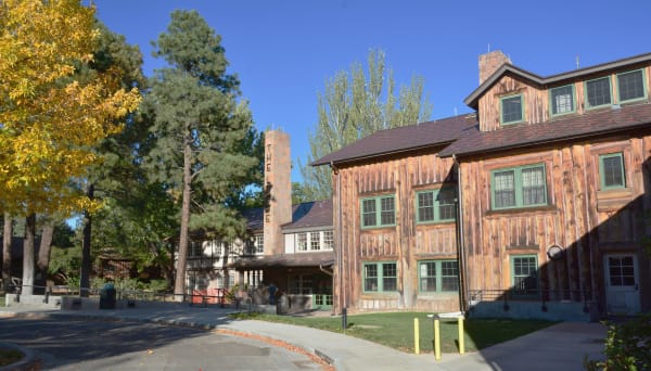 Fuller Lodge in Los Alamos, its log walls, green-trimmed windows and stone chimney under autumn trees