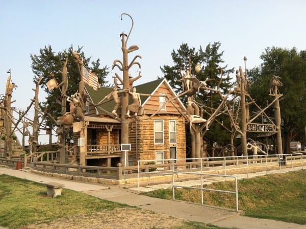 The limestone Cabin Home of S. P. Dinsmoor in Lucas, surrounded by his tall concrete tree sculptures.
