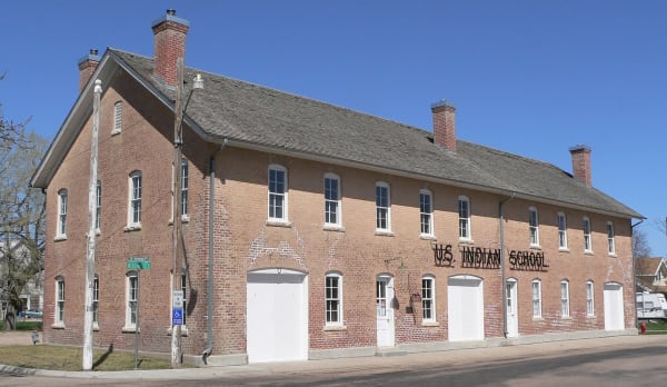 The long two-story brick shop building of the former U.S. Indian School in Genoa, its name painted across the front.