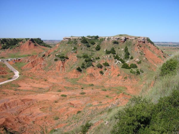 Red buttes capped with pale gypsum in the Gloss Mountains, seen from a mesa top.