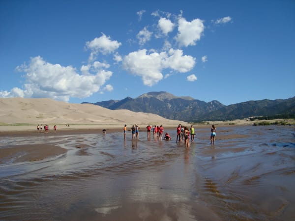 Visitors wading in Medano Creek below the Great Sand Dunes and the Sangre de Cristo Mountains