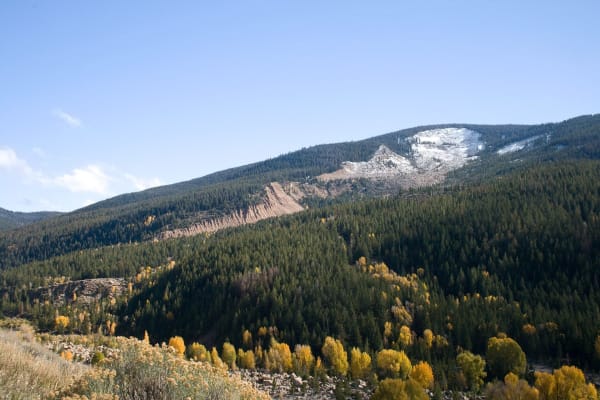 The bare scar of the Gros Ventre Slide running down the face of Sheep Mountain through dark forest, yellow aspens in the valley below