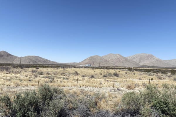Grassland and desert scrub stretching toward a range of rounded mountains in the Guadalupe Mountains National Park area.