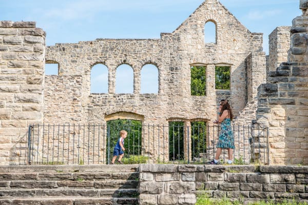 Visitors walking past the stone walls and empty window arches of the Ha Ha Tonka castle ruins.