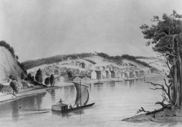 An 1857 lithograph of Hannibal on the Mississippi, the town spread below its bluffs with a sailing raft in the foreground.